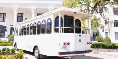White trolley bus parked near a white building.