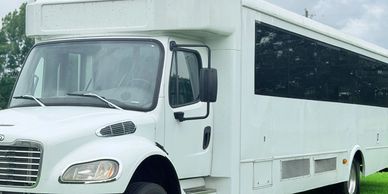 White shuttle bus parked on grass.