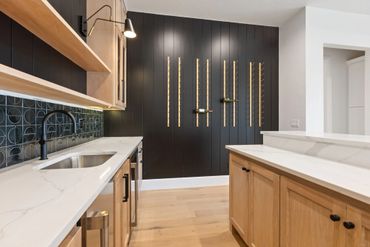 Modern kitchen with wooden cabinets and black accent wall.