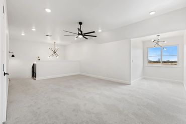 Spacious bright room with carpeted floor and modern ceiling fans.