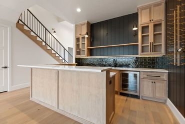 Modern kitchen with light wood cabinetry and a black backsplash.