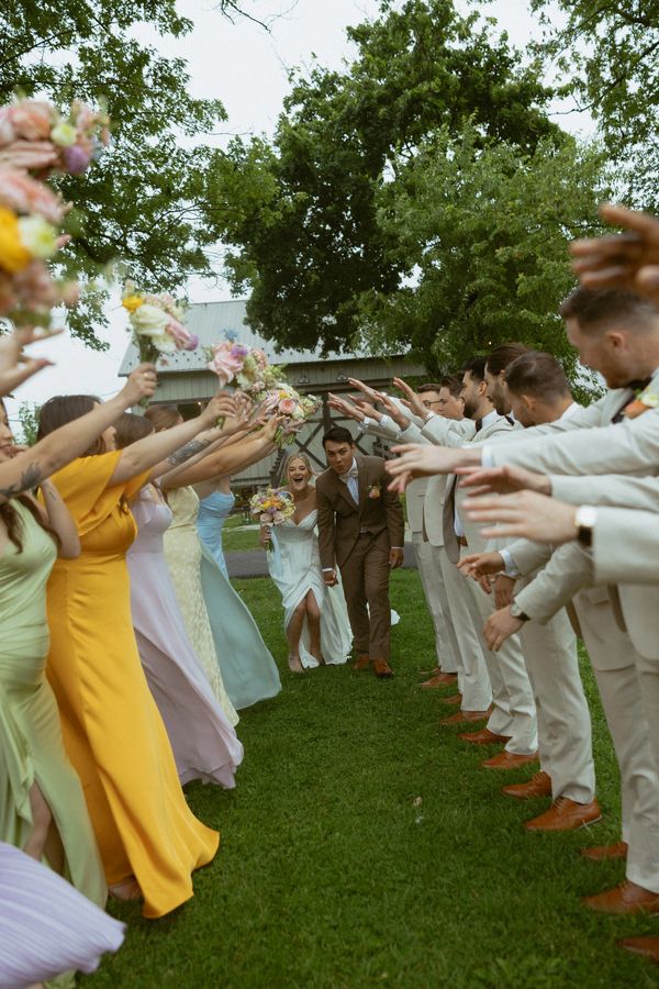 Bride and groom walking through cheering wedding party.