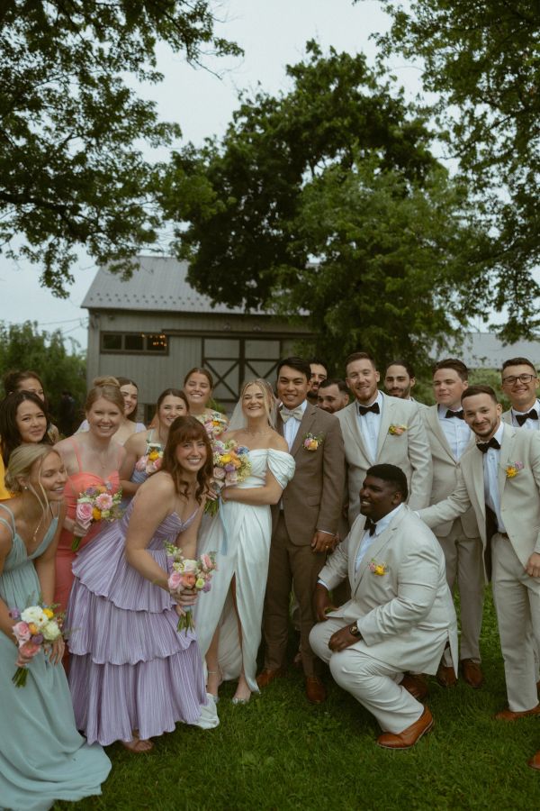 Wedding party with bride, groom, bridesmaids, and groomsmen outdoors.