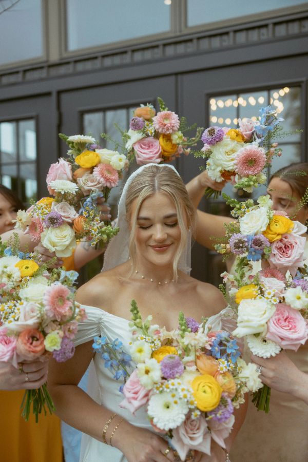 Bride surrounded by colorful flower bouquets.