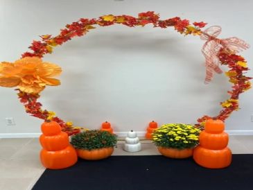 Fall-themed decorative arch with pumpkins and flowers.