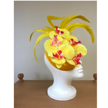 Yellow floral fascinator with feathers on a mannequin head.