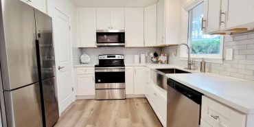 Modern white kitchen with stainless steel appliances.
