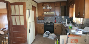 Cluttered kitchen with wooden cabinets and appliances.