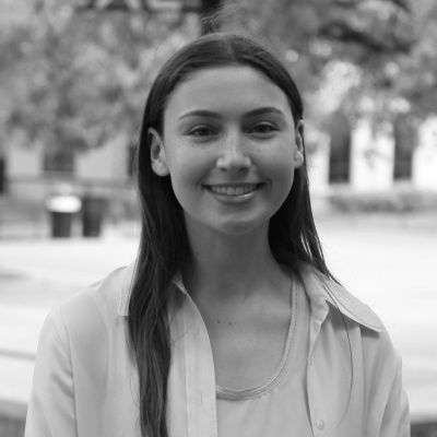 Young woman smiling outdoors in black and white photo.