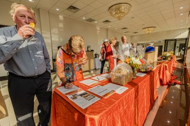 People browsing and signing at a silent auction table with orange cloth.