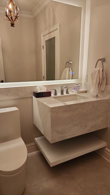 Salle de bain moderne avec lavabo en marbre et miroir éclairé.