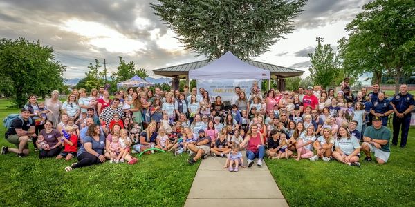 Large group gathered for a family reunion in a park under a tent.