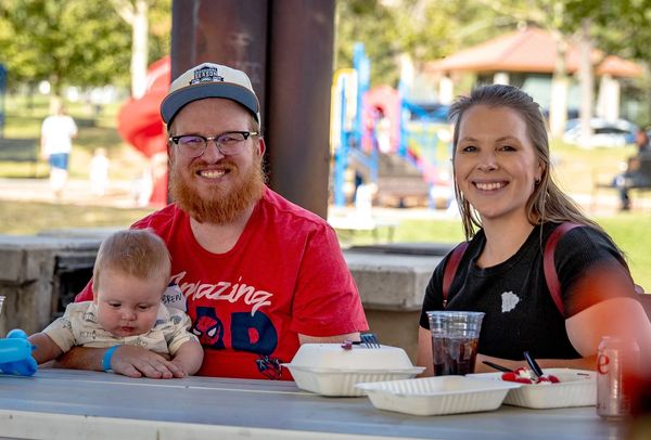 Happy family enjoying a meal outdoors at a park picnic.