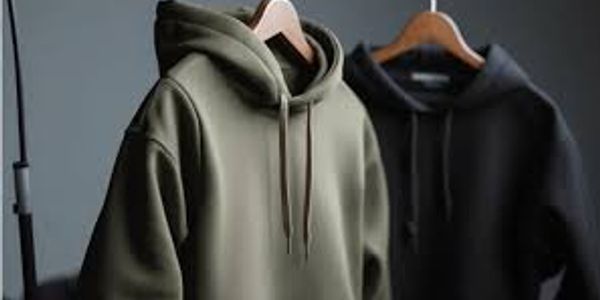 Two hooded sweatshirts hanging on wooden hangers, one olive green and one black.