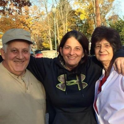 Three people smiling outdoors with arms around each other.