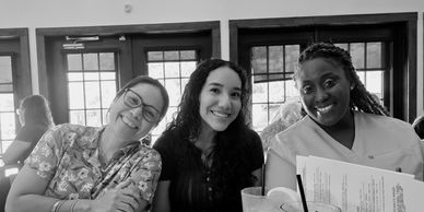 Three women smiling together at a restaurant table with menus and drinks.