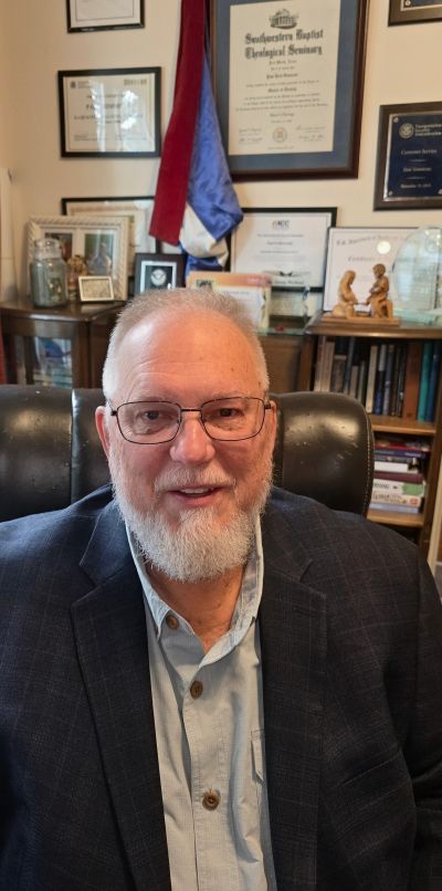 Elderly man with white beard and glasses in an office.