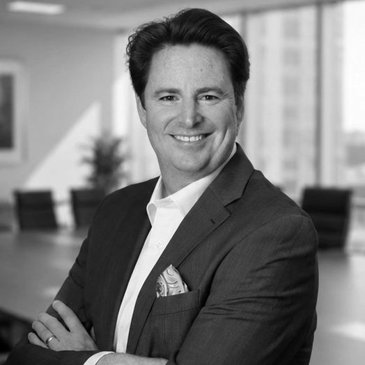 Confident man in business attire smiling with arms crossed.