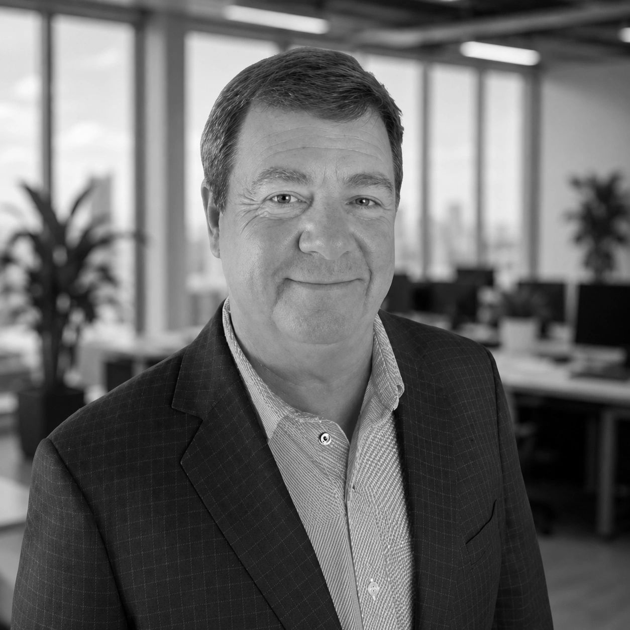 Professional man in a suit smiling in an office setting.