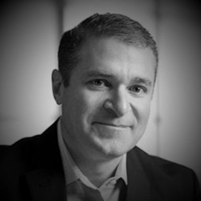 Black and white portrait of a smiling man in business attire.