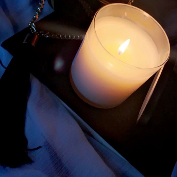 Burning candle on a book next to perfume bottle 