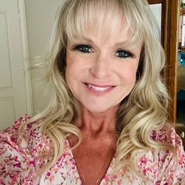 Smiling woman with blonde hair in floral top.