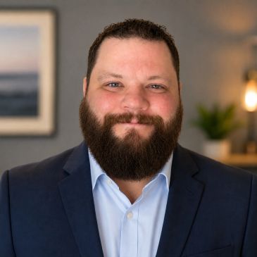 Bearded man in a suit smiling.