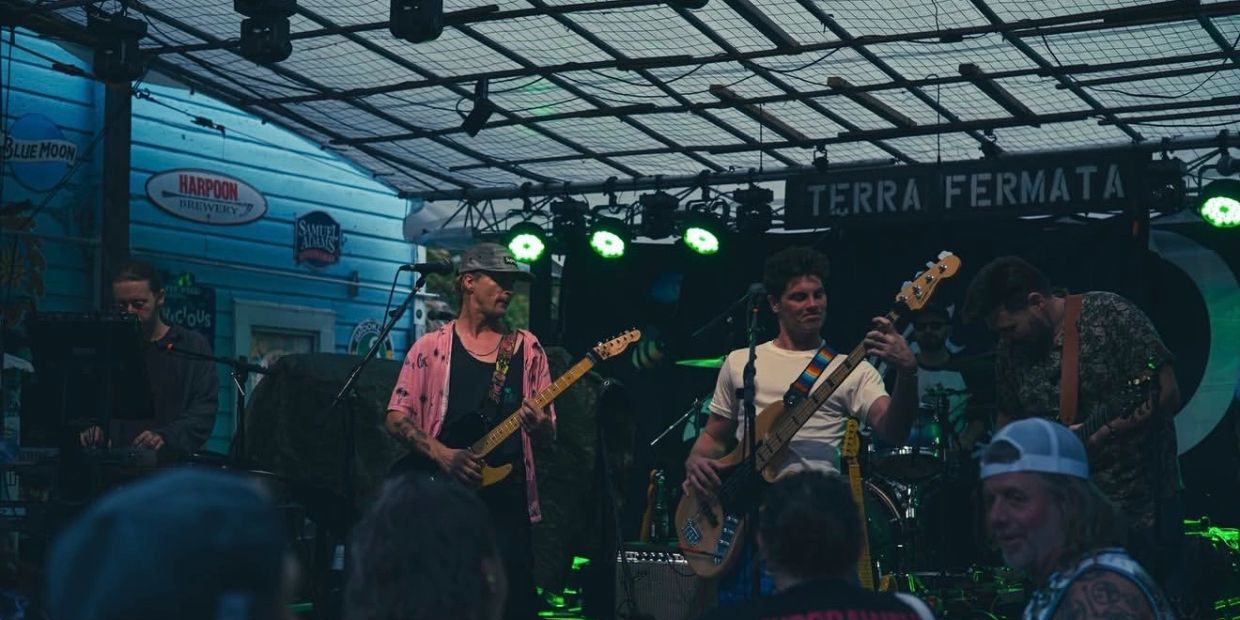 Band performing live on stage with instruments under green lights.