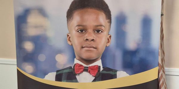Young boy wearing a red bow tie and plaid vest.