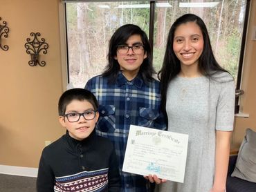 Holding up their wedding license, Jerry & Myte pose with their young son