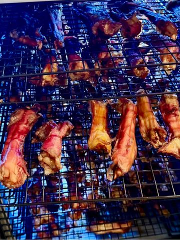 Meaty bones grilling over a flame on a barbecue rack.