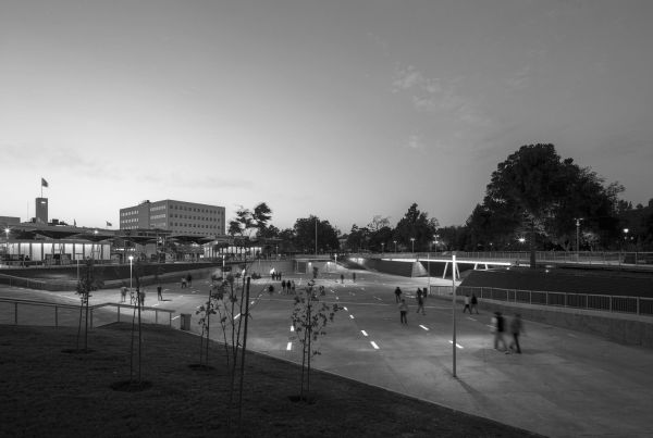 Evening scene at a modern public park with people strolling and relaxing.
