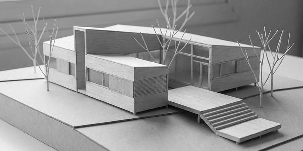 Modern architectural model of a minimalist house with trees and stairs.