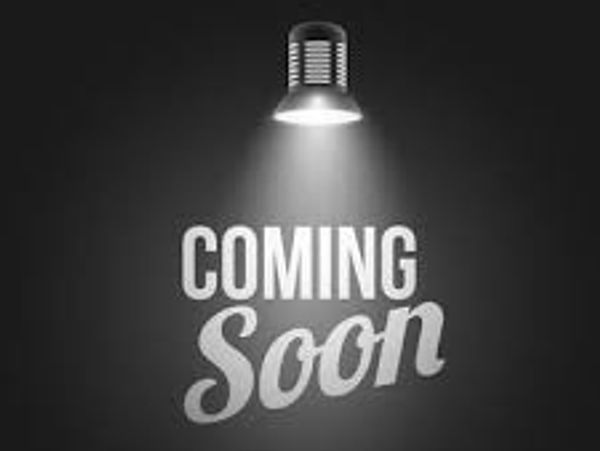 Black background with 'Coming Soon' text illuminated by spotlight.