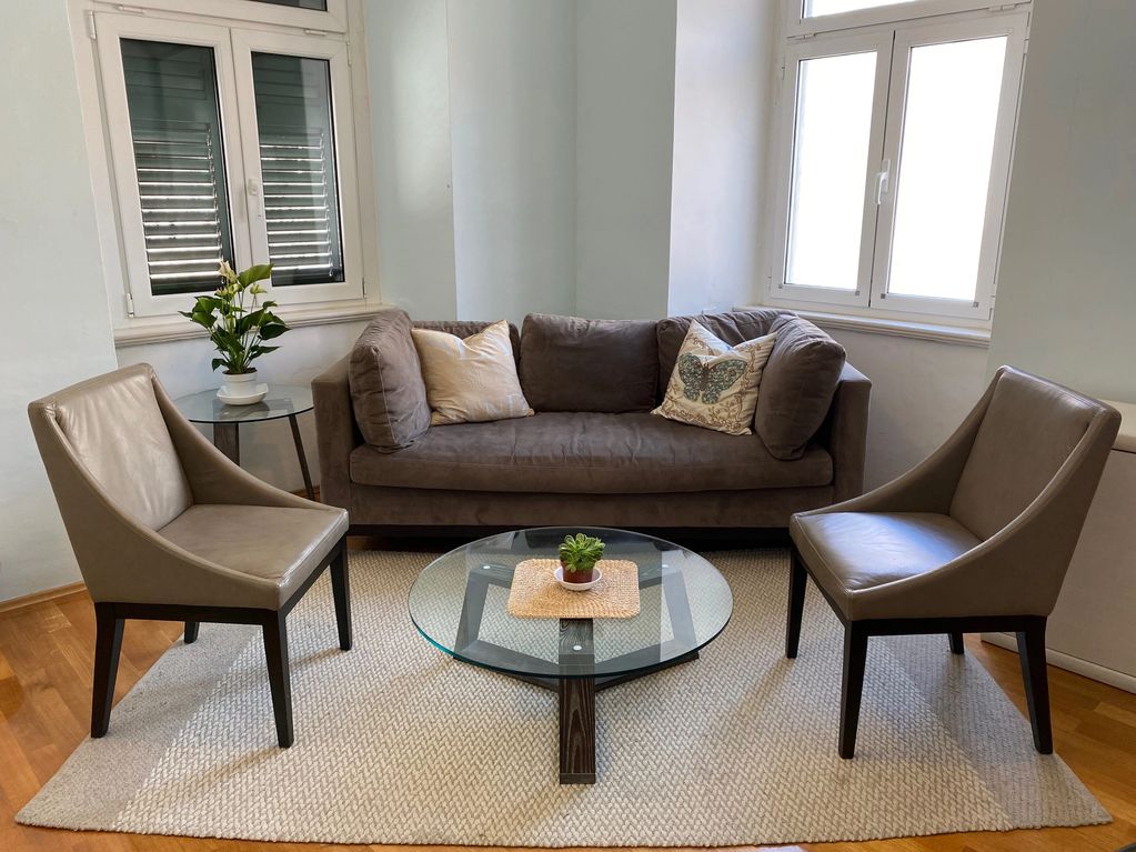 Living room with wood floors, grey couch and 2 chairs and coffee table.