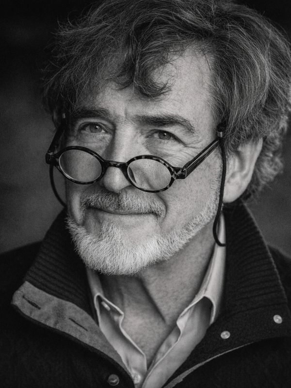 Black and white portrait of a smiling older man with glasses and a beard.