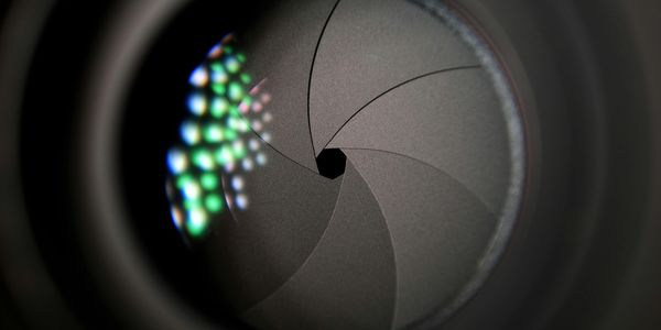 Close-up of a camera lens aperture with colorful reflections.