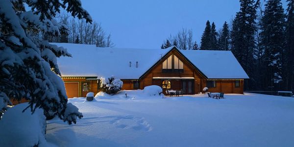 Snow-covered house lit up at twilight.