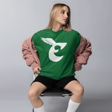 woman sitting on a chair wearing a kelly green philadelphia eagles retro logo t shirt with a jacket
