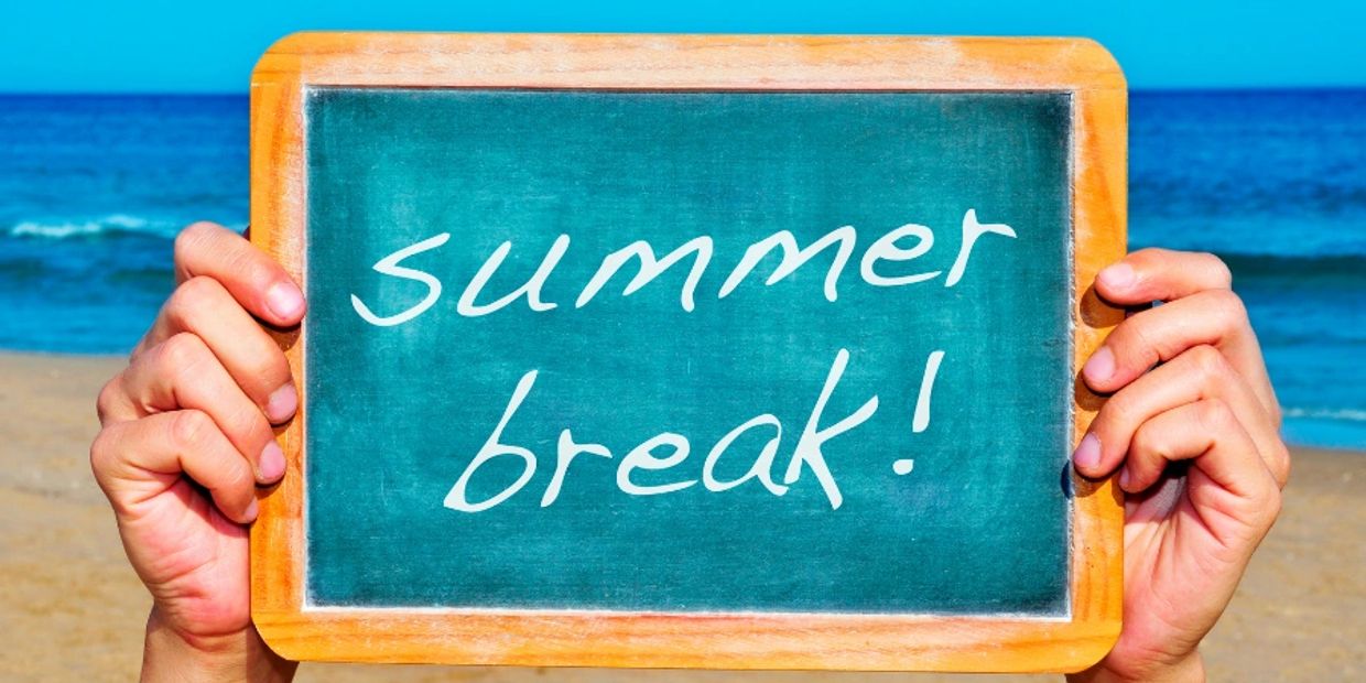 Chalkboard reading 'summer break!' held at the beach.