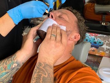 Guy laid back getting nose waxed