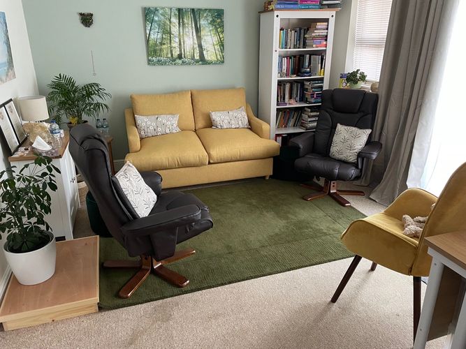An overview of my therapy room, showing a soft mustard colour sofa and three comfortable arm chairs 