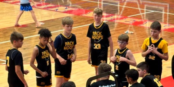 Young basketball players in black and yellow jerseys standing during a game.