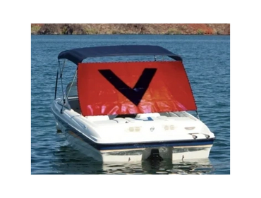 A boat on water with a large red and black cover displaying the letter V.