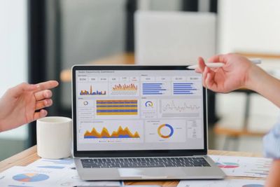 Two people discussing data visualizations on a laptop screen.