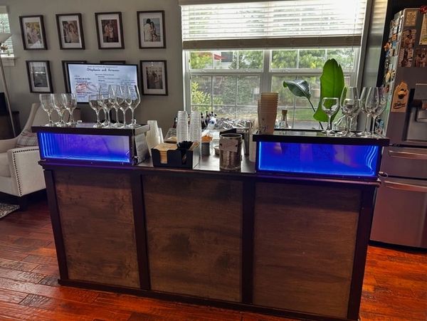 Home bar setup with glasses and blue LED lights on a wooden counter.