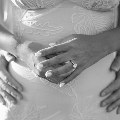 Close-up of hands on a pregnant belly with a ring.
