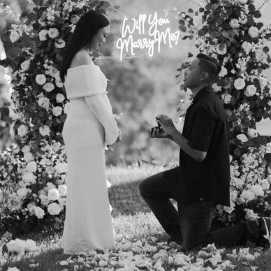 Man proposing to woman surrounded by flowers.