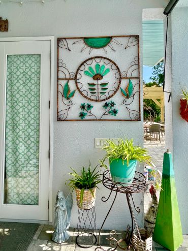 Decorative wall art with plants and statues on a bright patio.