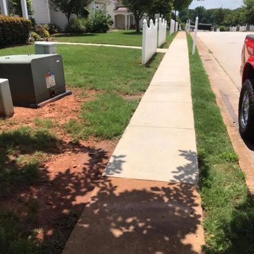 Sidewalk before and after pressure washing, showing red Georgia clay removed for a bright finish.
